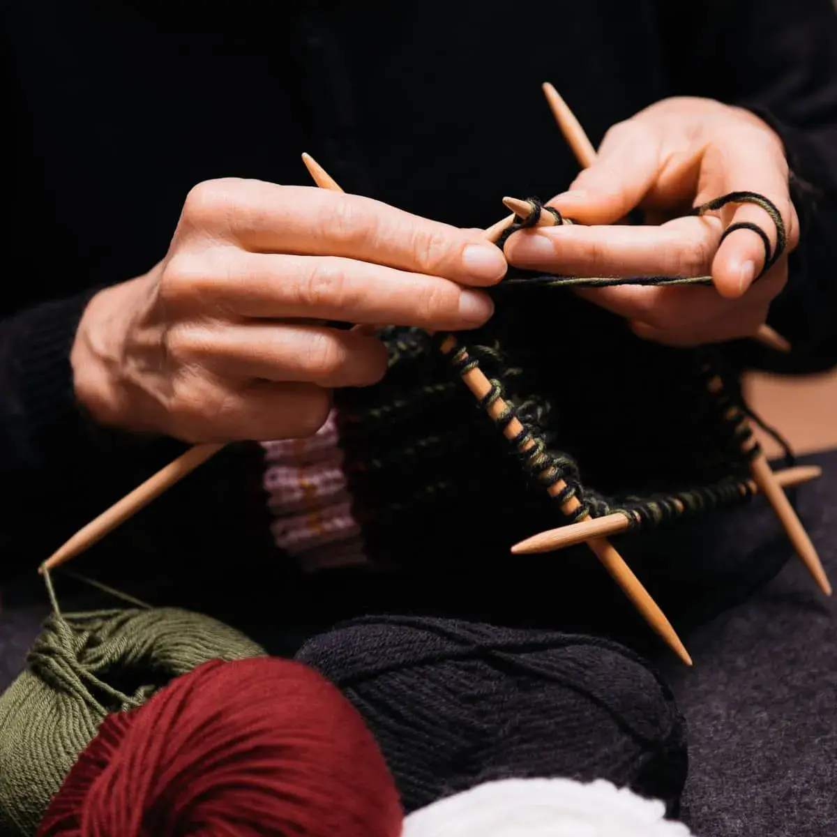 Hände stricken einen Loop aus dickem Garn