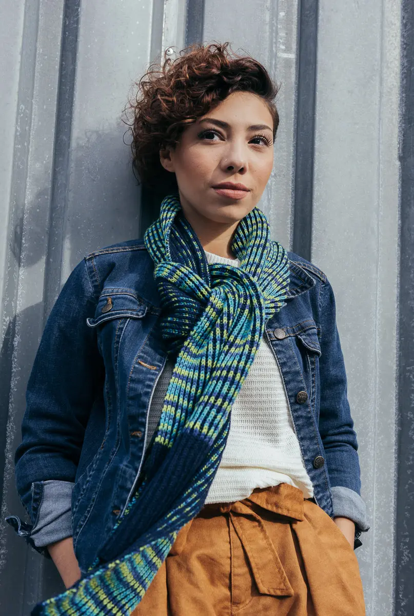 Geknoteter Rippenschal in Blau und Limettengrün über weißem Pullover und Jeansjacke