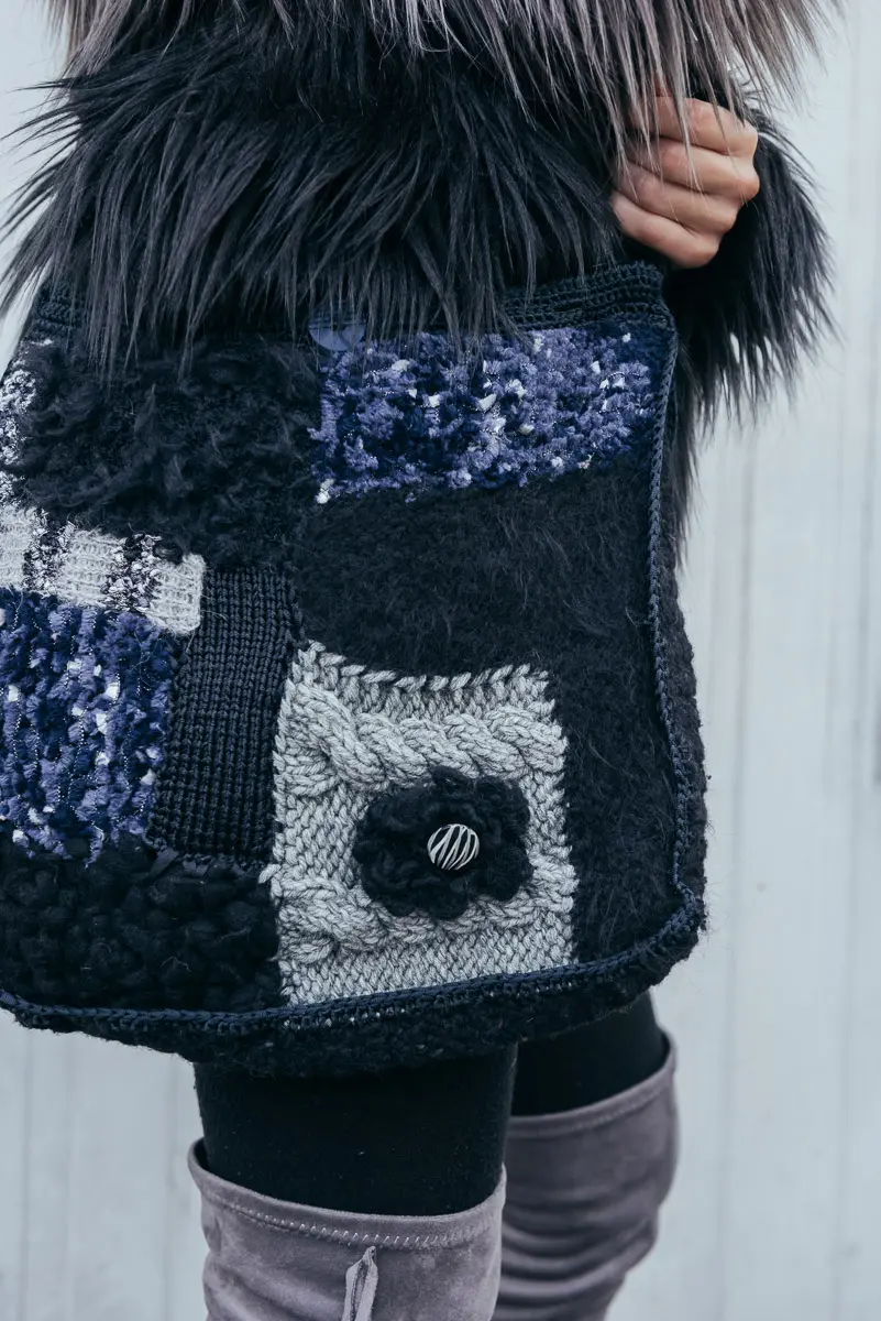 Detail einer Patchworktasche aus Strickquadraten in Blau und Grau mit aufgesetzter Strickblume