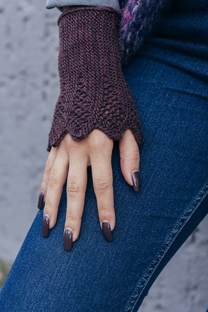 Handdetail mit weinrotem Pulswärmer in feinem Strickmuster, Hand liegt auf Jeansstoff