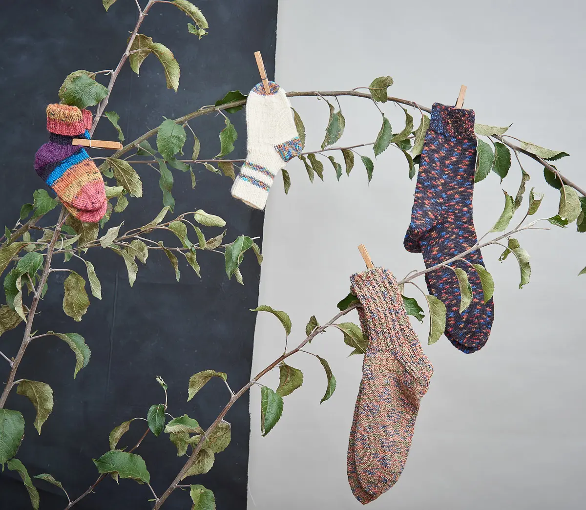 Vier einzelne Socken in Ringel-, Tupfen- und Melangemustern, darunter ein winziges Babysöckchen